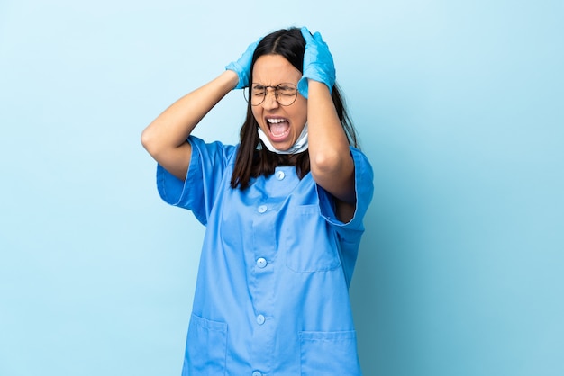 Cirurgião mulher sobre parede azul estressado oprimido