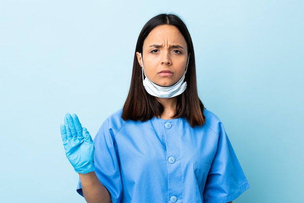 Cirurgião mulher sobre parede azul, fazendo o gesto de parada