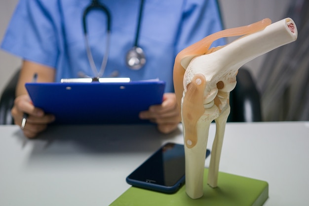 Foto cirurgião ortopédico lê relatório de substituição do joelho de um paciente
