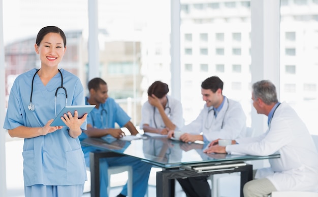 Cirurgião usando tableta digital com grupo em torno da mesa no hospital