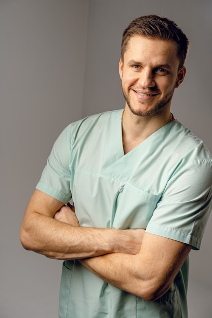 Cirurgião vestindo túnica médica, sorrindo e posando. belo médico feliz posando