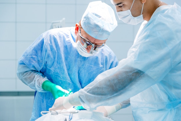 Foto cirurgiões em lentes binoculares operam no paciente na clínica