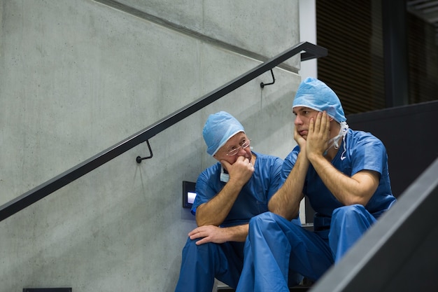 Cirurgiões preocupados sentados na escada