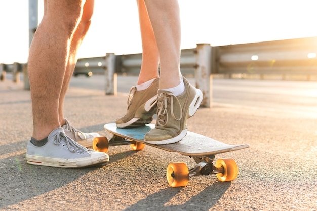 Cita de pareja. Chica de pie sobre un longboard junto a su novio en la calle al atardecer.