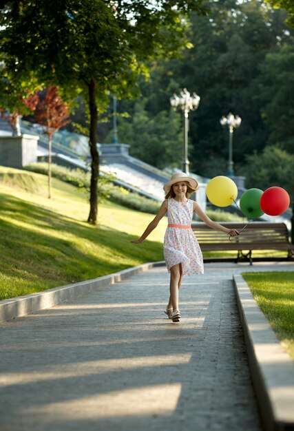Cita romántica para niños en el parque de verano, amistad, primer amor. Niña con globos de aire. Niño divirtiéndose al aire libre, infancia feliz