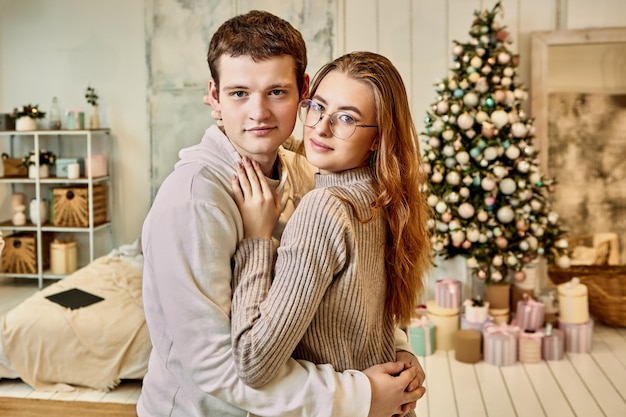 Cita romántica en la víspera de navidad abrazos de pareja joven cerca del árbol de navidad