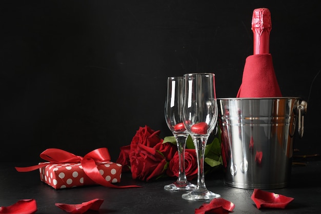 Citas románticas con vino espumoso, regalo, ramo de rosas rojas sobre negro. Celebración por San Valentín.