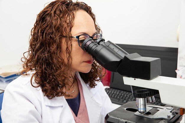 Foto citólogo observando muestras de frotis de papanicolaou a través de un concepto de análisis médico por microscopio