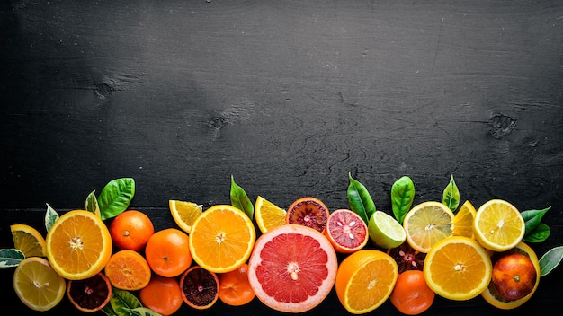 Cítricos frescos Limón naranja mandarina lima Sobre un fondo negro Vista superior de madera