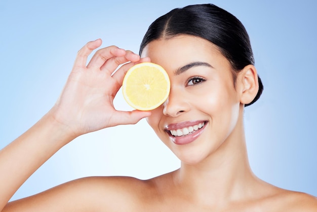 Cítricos de limón y mujer con fruta de vitamina C para desintoxicación facial aislada sobre fondo azul de estudio Cosméticos para el cuidado de la piel y retrato de modelo de autocuidado que cubre los ojos con alimentos para una piel suave