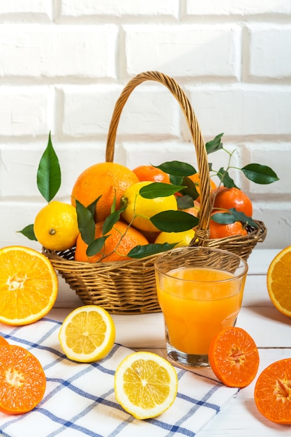 Los cítricos de limón naranja en una canasta y un jugo sobre un fondo claro, hacen una dieta saludable.