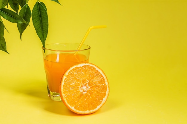 Cítricos de limón naranja en una cesta y jugo sobre un fondo amarillo