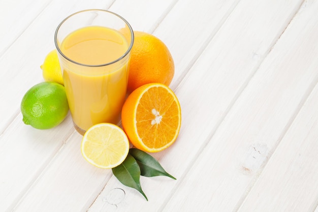 Cítricos y vaso de jugo de naranjas, limas y limones