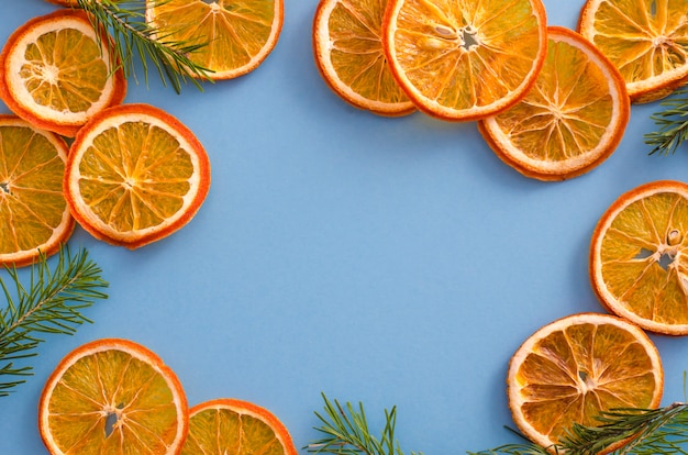 Citrinas secadas das laranjas das fatias na luz - fundo azul. Decoração de aroma natural caseiro.