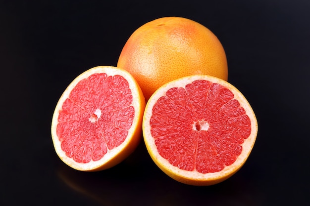 Citrino. Grapefruit fatiado e inteiro em um espaço escuro