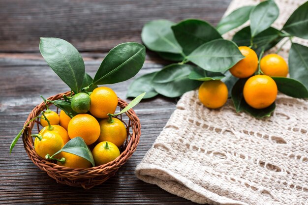 Citrus Calamondin com folhas na cesta guardanapo de linho na placa de madeira.