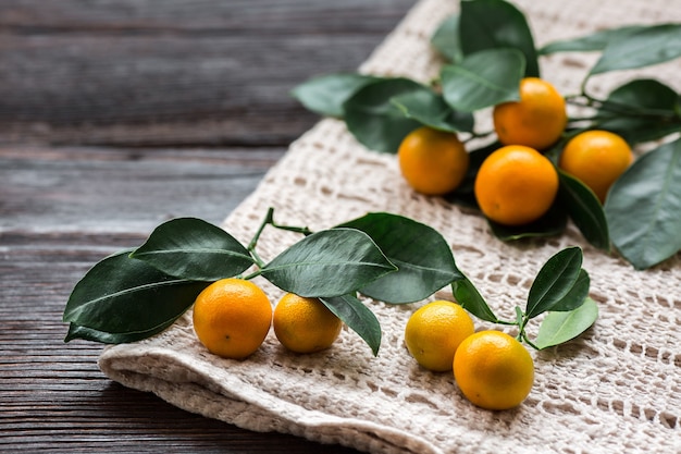 Citrus Calamondin com folhas no guardanapo de linho na placa de madeira.