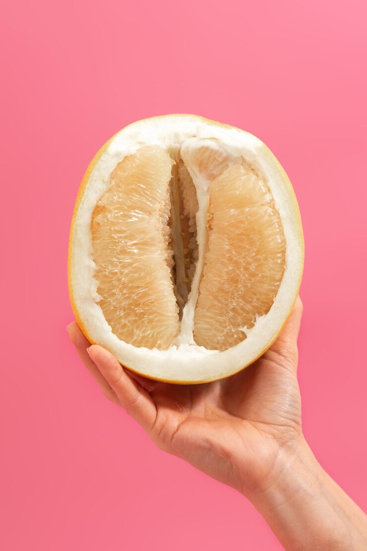 Citrus maxima à disposição em uma foto vertical de fundo rosa