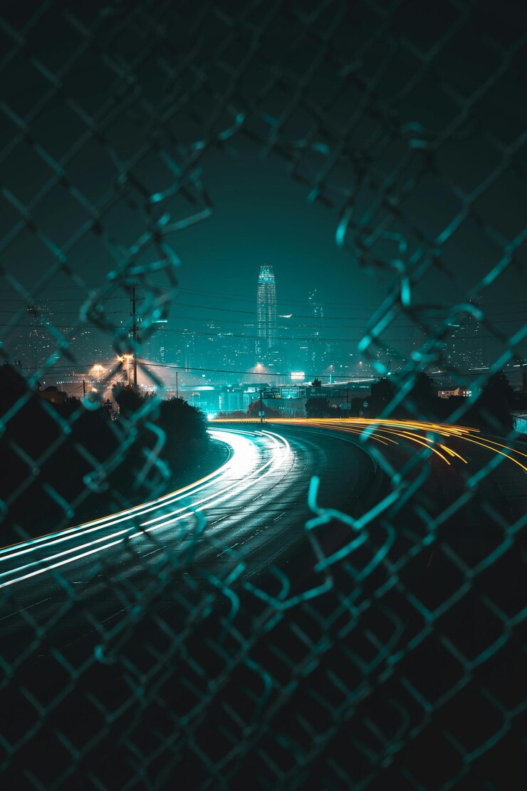City Lights Through the Fence Nighttime Urban Photography