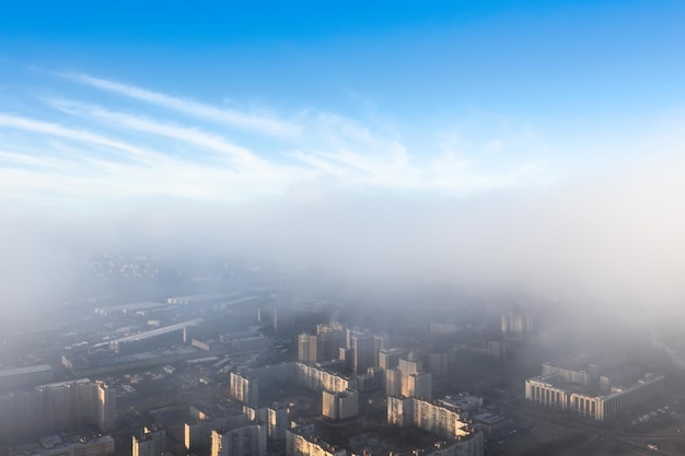 Foto la ciudad está bajo una capa de niebla y nubes bajas desde arriba hay un cielo azul claro