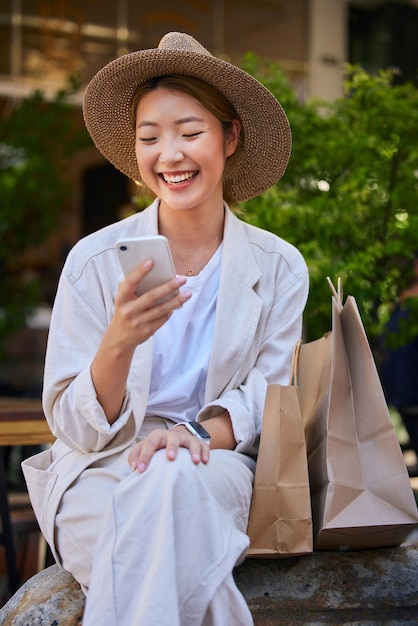 Ciudad de compras y mujer en Japón con teléfono inteligente para el sitio web de comercio electrónico fintech y acuerdo de Internet sobre promoción y descuento de productos de venta Celular asiático o niña japonesa y bolsa de compras en el centro comercial