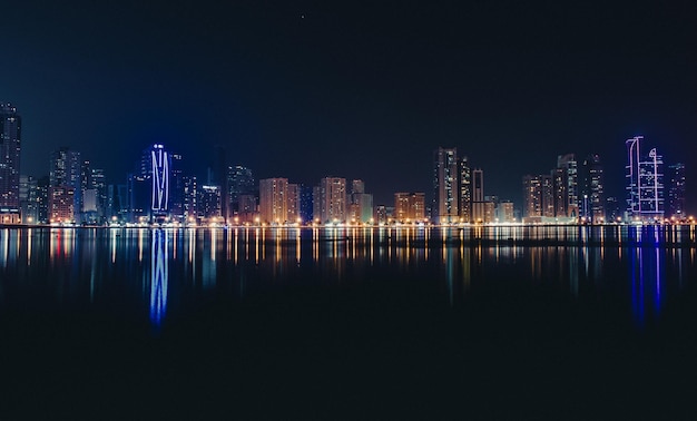 Ciudad iluminada reflejada en el río contra el cielo despejado por la noche