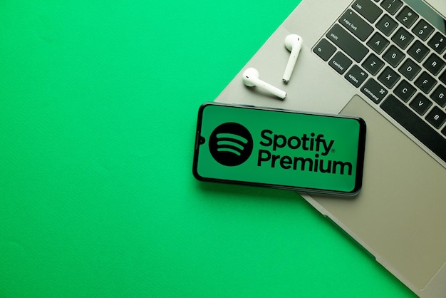 Ciudad de Kyoto Japón 31 de julio de 2023 Logo Spotify en un teléfono inteligente cerca de una computadora portátil moderna sobre fondo verde