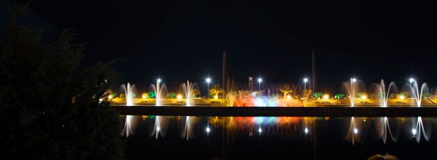 una ciudad por la noche con una fuente en primer plano