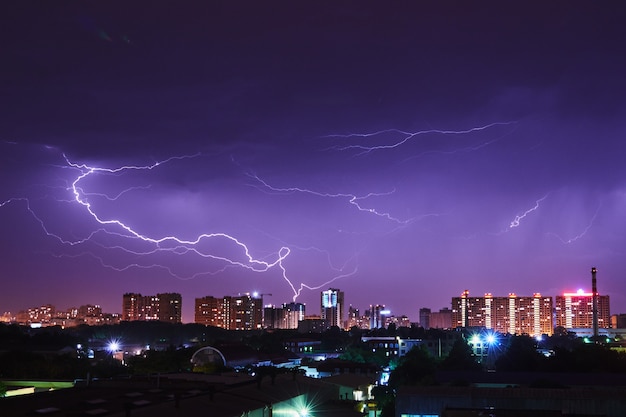 Ciudad nocturna con destellos brillantes en un cielo tormentoso