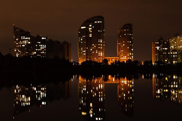 Ciudad nocturna con reflejo de casas en el río.