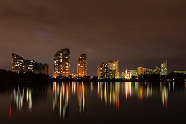 Ciudad nocturna con reflejo de casas en el río.