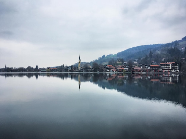 Una ciudad se refleja en el agua con una montaña al fondo.