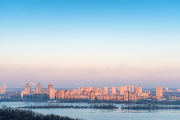 Foto ciudad sobre el río al atardecer. ver el paisaje urbano con edificios, kiev, ucrania