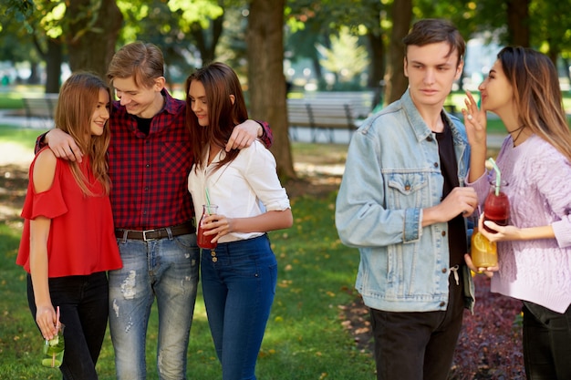 Ciúme e inveja no relacionamento de amigos. jovens alegres com coquetel de desintoxicação em festa de verão ao ar livre