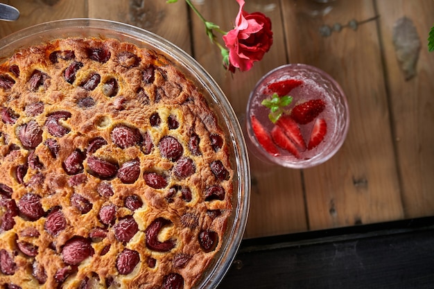 Clafoutis com cereja em um fundo de madeira, sobremesa francesa tradicional de frutas doces.