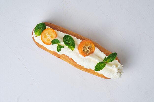 Éclair com creme de manteiga branca, decorado com hortelã e kumquat.