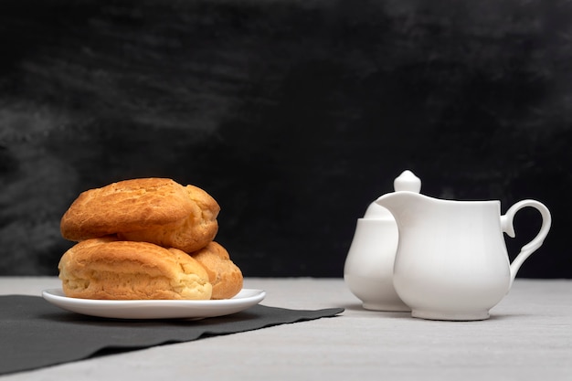 Éclairs caseiros e creme. Éclairs franceses tradicionais. Superfície cinzenta.