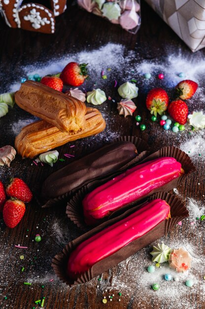 Éclairs de sobremesas francesas tradicionais com esmalte na mesa de doces