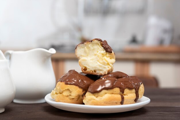 Éclairs encharcados de chocolate com creme de manteiga na chapa branca.