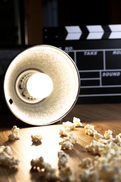 Clapper de película con foco iluminado y palomitas de maíz.