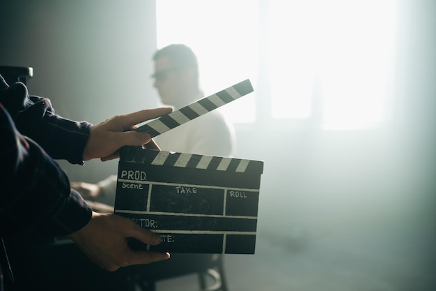 Clapperboard o portapapeles en las manos Guy está dirigiendo y filmando cine retro o una película vintage El hombre compositor toca el piano viejo