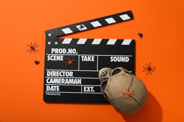 Clapperboard und Halloween-Dekorationen auf orangefarbenem Hintergrund