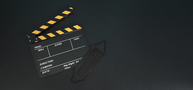 Claquete amarela ou ardósia do filme com máscara preta ou máscara médica isolada. é usado no cinema, produção de filmes e indústria do cinema em fundo preto. Filme-19 ou conceito de distância social.