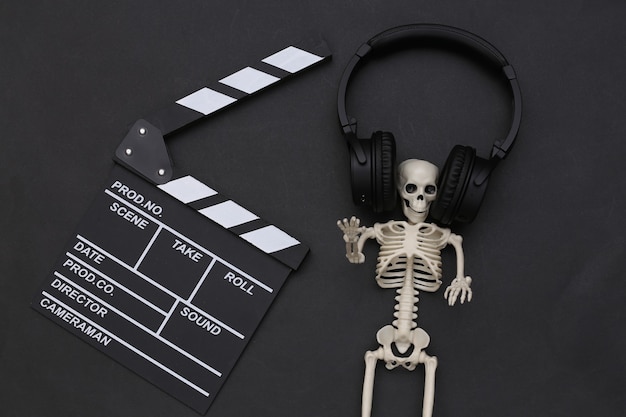 Claquete e esqueleto do filme em fones de ouvido estéreo em fundo preto. filme de terror. tema de halloween. vista do topo