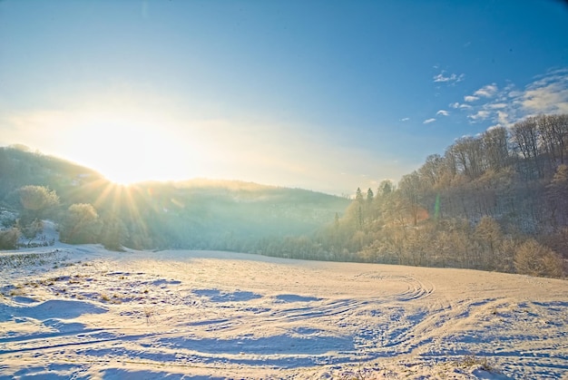 Clareira coberta de neve em um dia de inverno ao nascer do sol nas montanhas