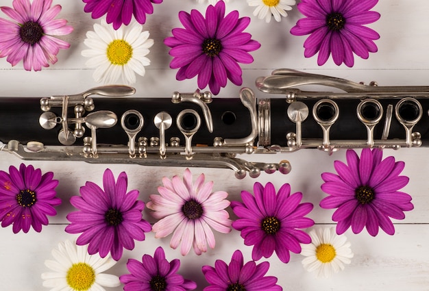 Foto clarinete con flores en superficie de madera