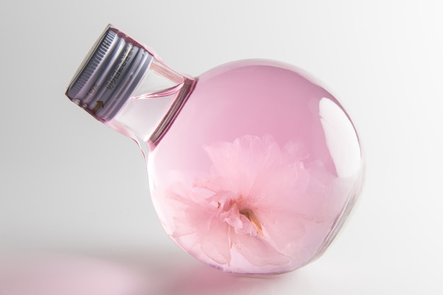 Claro licor de Sakura rosa en botella con flor de sakura dentro para sprin