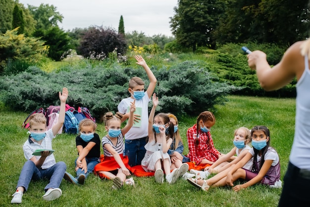 Una clase de escolares enmascarados participa en un entrenamiento al aire libre durante la epidemia. Regreso a la escuela, aprendiendo durante la pandemia.