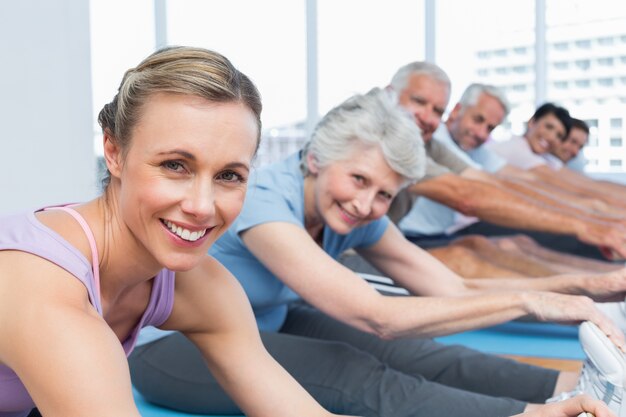 Clase estirando las manos a las piernas en la clase de yoga