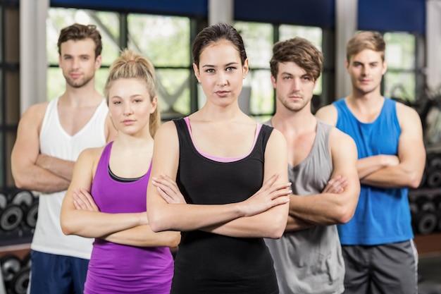 Clase de gimnasia con brazos cruzados en gimnasio.